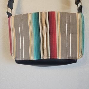 black faux leather crossbody bag featuring a colorful striped fabric accent 